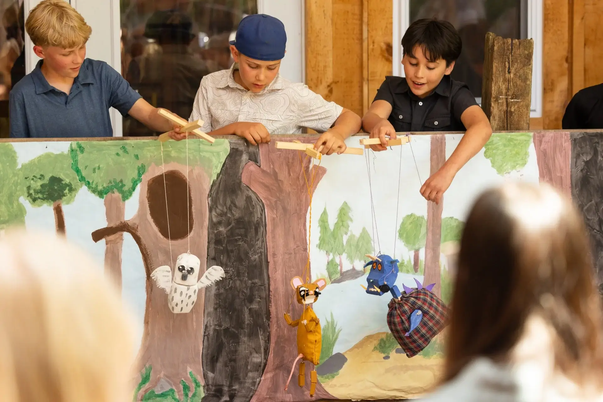 WONDERfield students performing a handmade marionette puppet show against a hand-painted forest backdrop